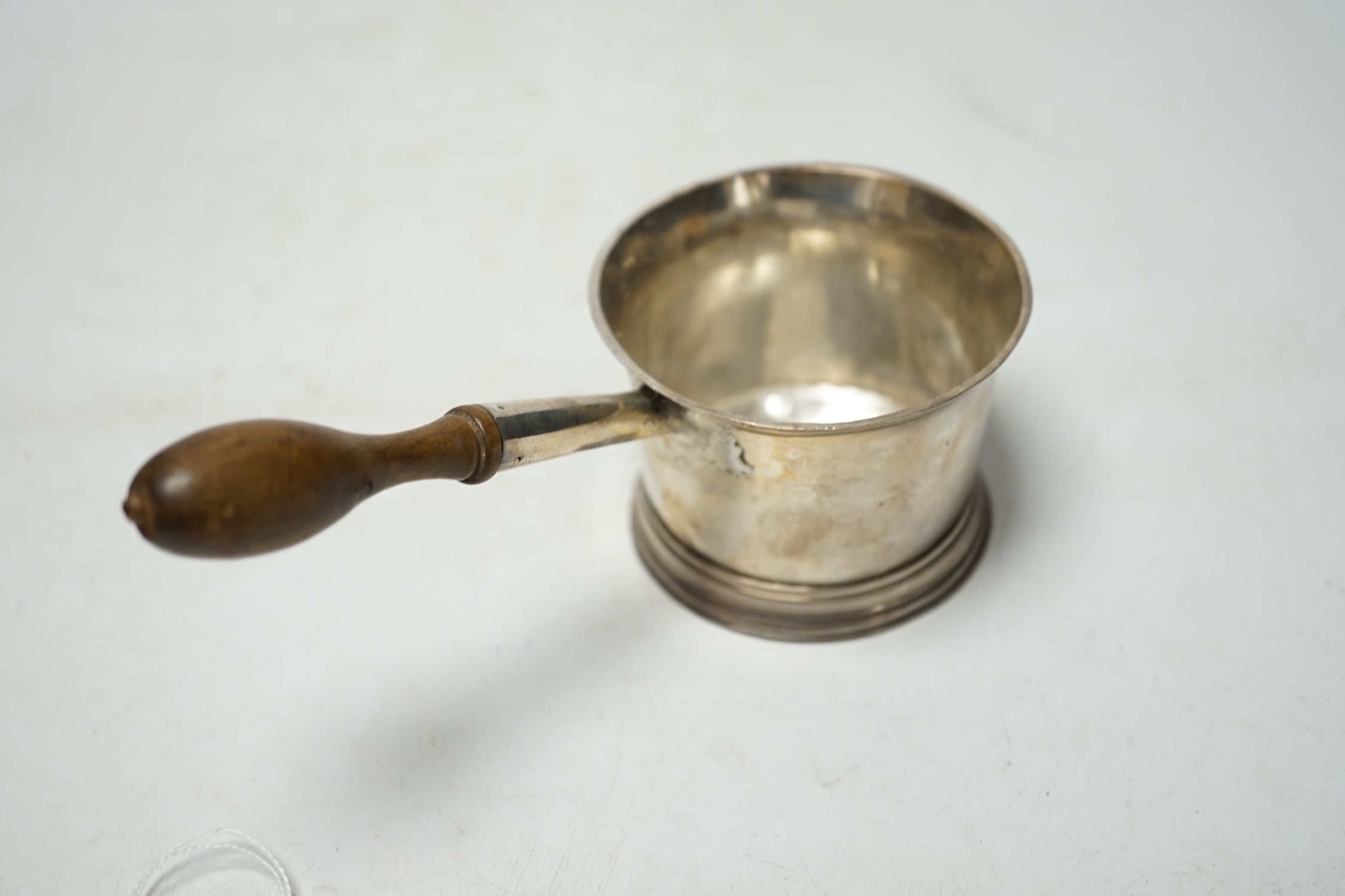 A late 18th/early 19th century silver brandy saucepan, with turned wooden handle, rubbed marks to the base, 17.5cm. Condition - poor